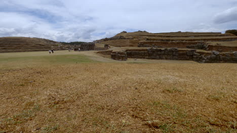 wide shot of tourists at the fort ruins of sacsayhuaman, cusco, peru