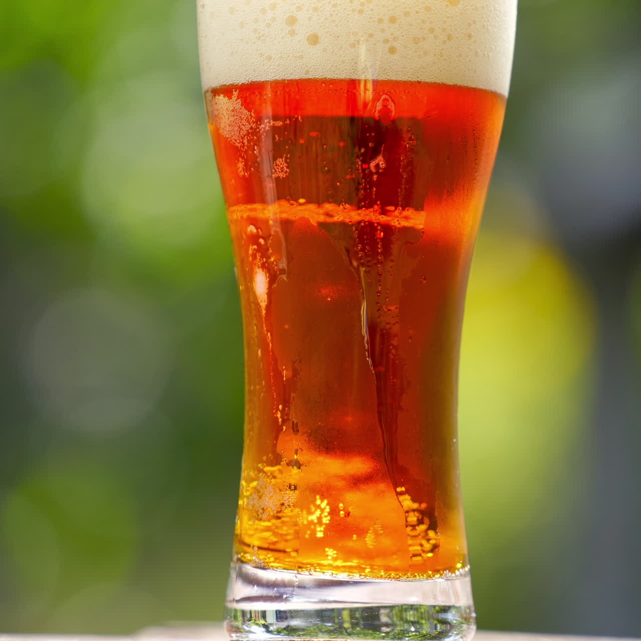 Fresh beer with bubbles in glass. Cold brewed drink in a glass with water drops over blur background. Craft beer close up.