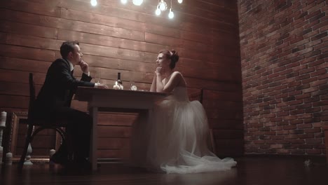 young couple in a wedding attire sitting in a restaurant and talking during dinner slow motion