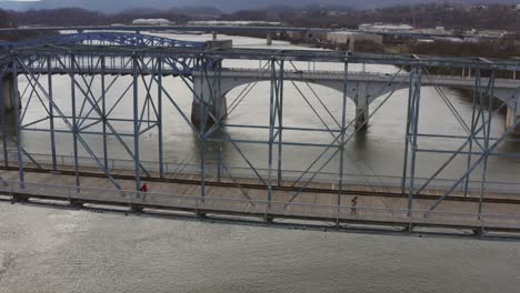 Menschen,-Die-Auf-Einer-Großen-Fußgängerbrücke-über-Einen-Fluss-Laufen