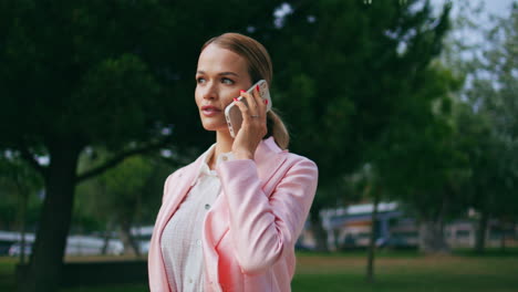 relaxed business woman calling cellphone at calm walk green park close up.