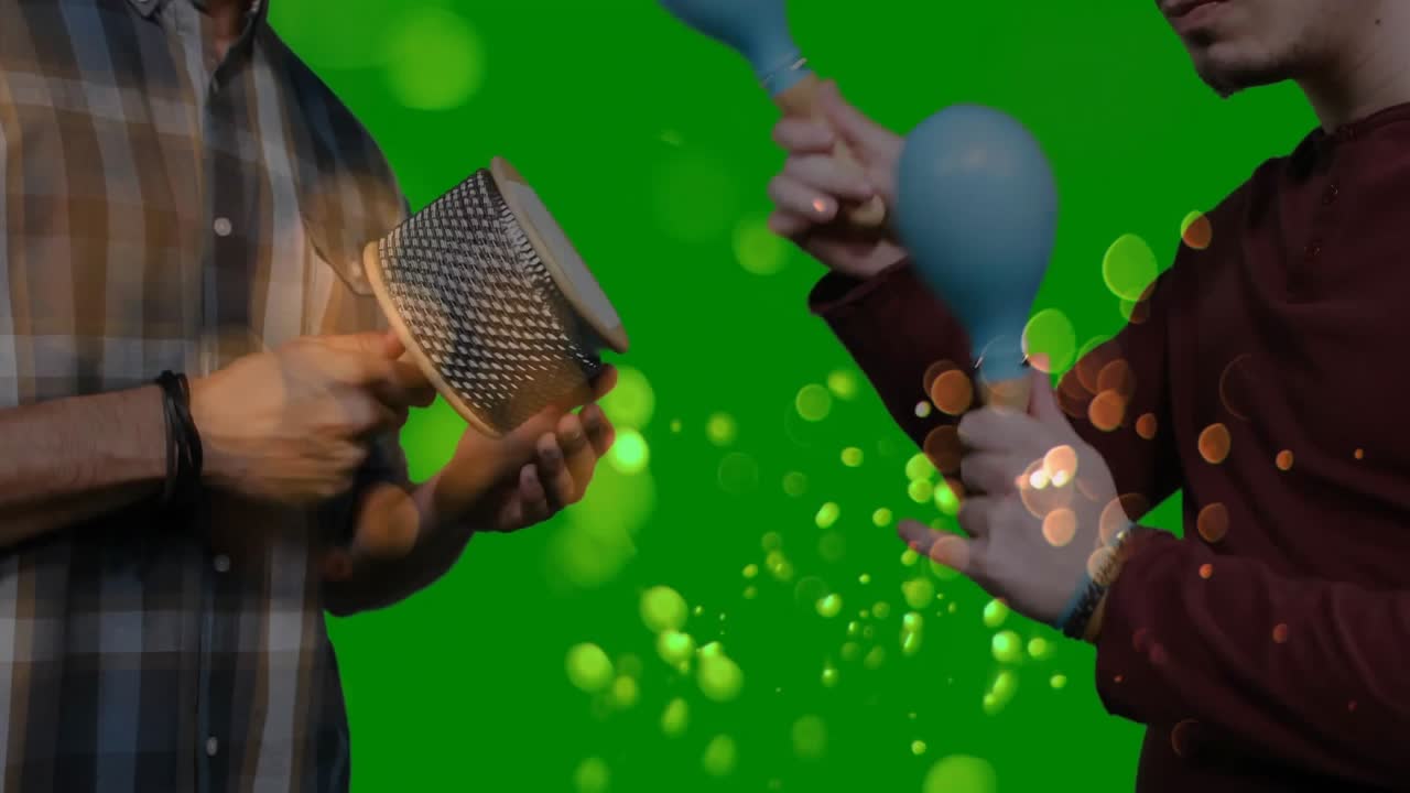 Musicians rotating cabasa and shaking maracas on green screen initiating bokeh for music production