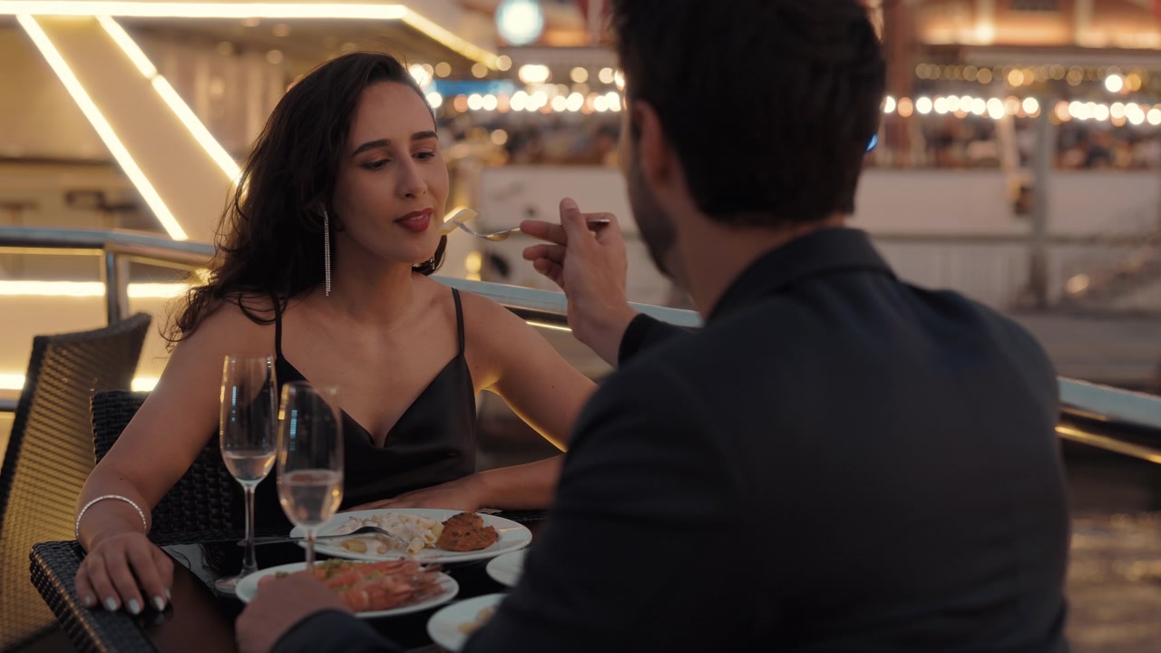 Uomo che imbocca una donna durante una cena romantica in un ristorante all'aperto