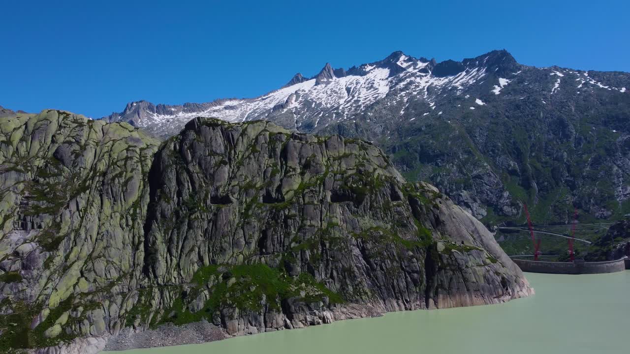Aerial drone panning shot over dam under construction in Grimsel Pass, Swiss Mountain, Switzerland on a sunny day