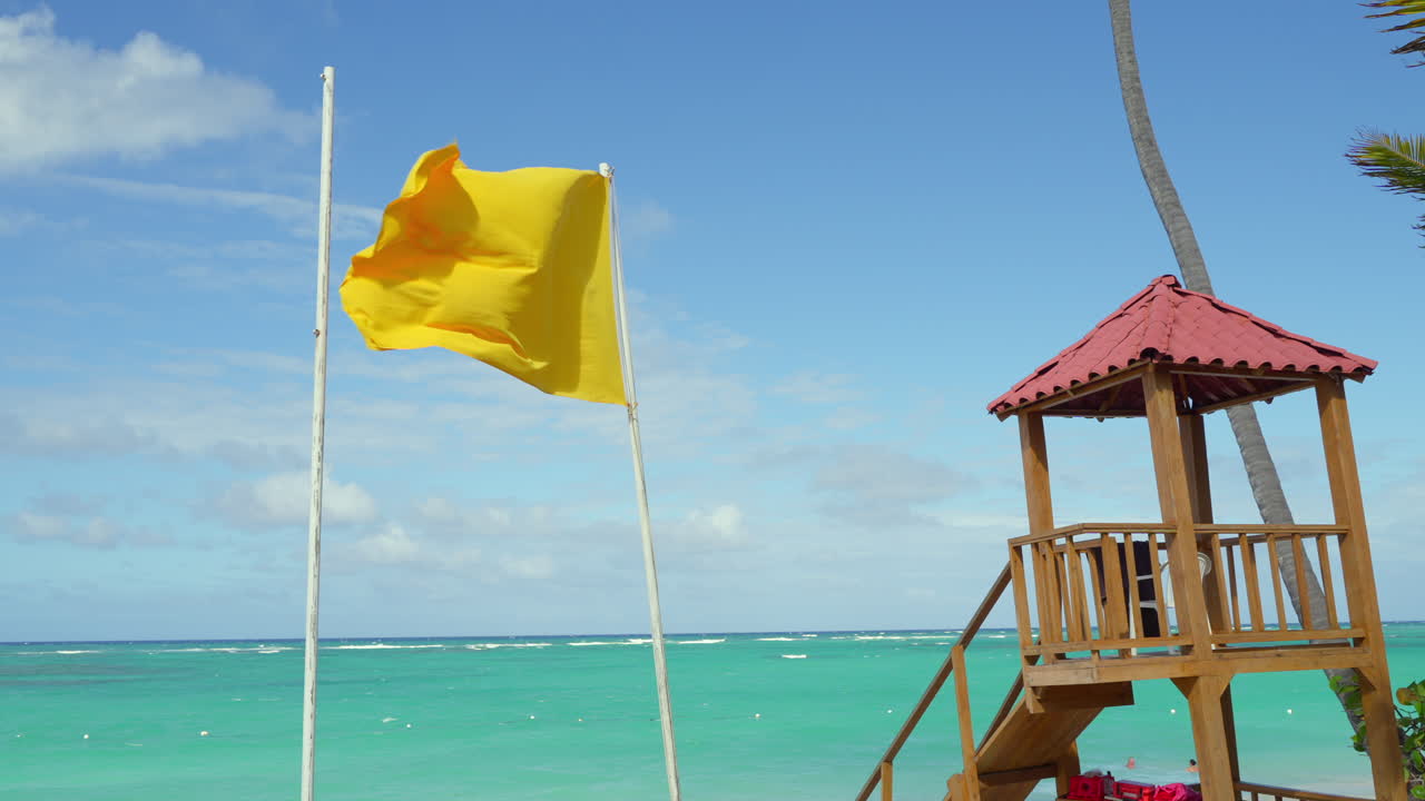 Yellow Caution Flag On Mast Waving In Wind On Beach. Slow Motion