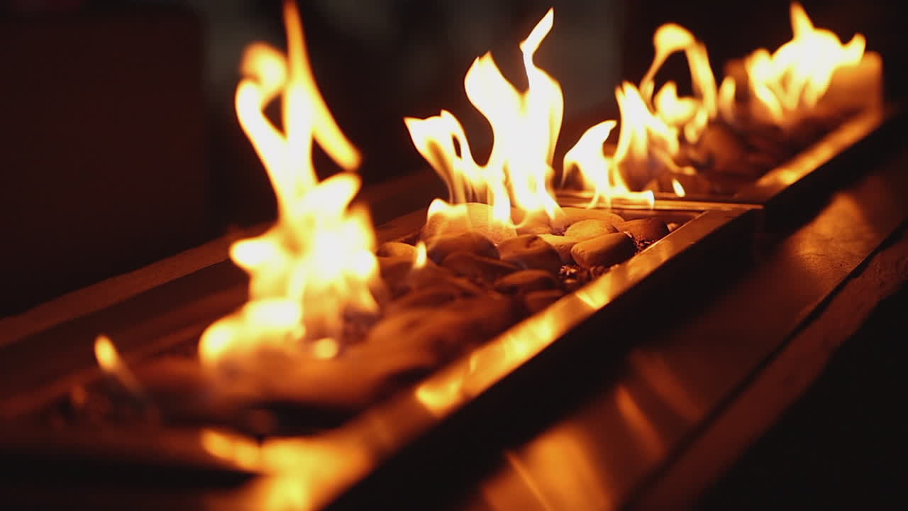 Slo mo flames burn orange in stone gas fireplace, diagonal decor