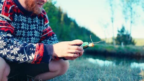 a man with ice fishing rod and bait near creek