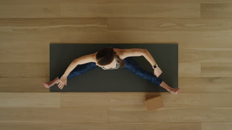 Vista-Superior-De-Una-Mujer-De-Yoga-Practicando-Una-Pose-De-Gran-Angular-Sentada-De-Lado-En-Un-Estudio-De-Ejercicios-Disfrutando-De-Un-Estilo-De-Vida-Saludable-Practicando-Meditación-En-Una-Colchoneta-De-Ejercicios