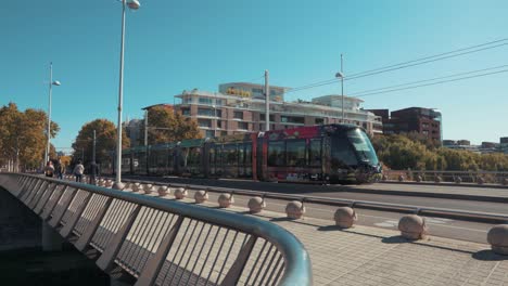 a tram is moving towards the city in the middle of a sunny day, montpellier - france