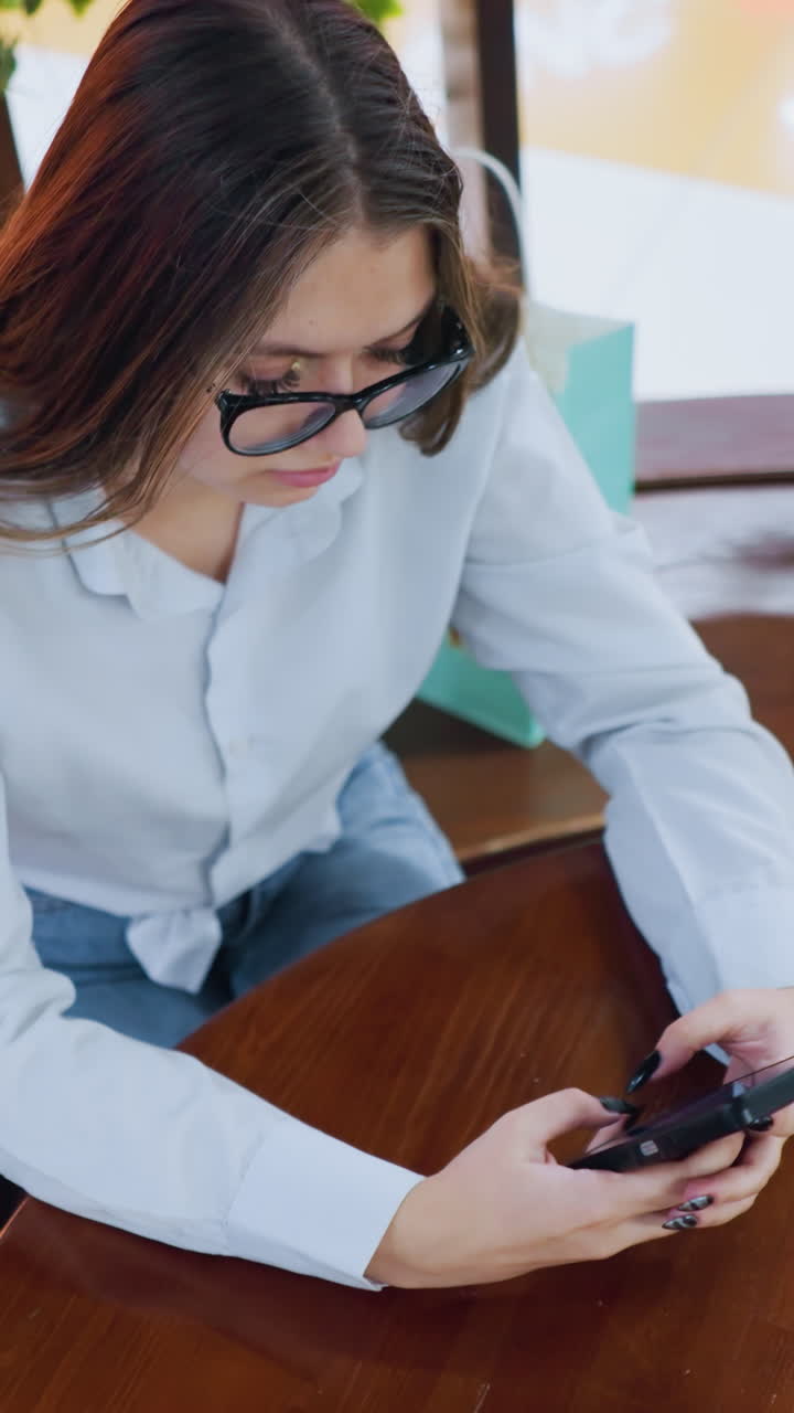 vista aérea de una mujer joven conversando con un socio de negocios por teléfono con la mano colocada sobre una mesa redonda en un espacio de trabajo moderno y decorado, demostrando comunicación remota