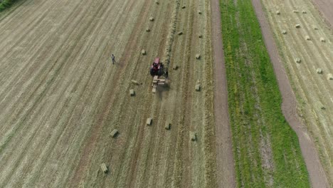 Haystacks-on-the-field-and-tractor-working-on-the-natural-green-background