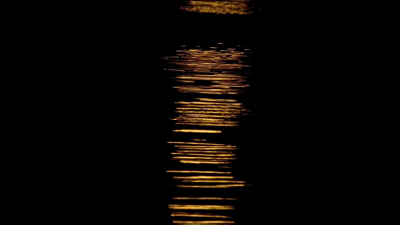 Luce dorata scintillante che si riflette sull'acqua scura notturna
