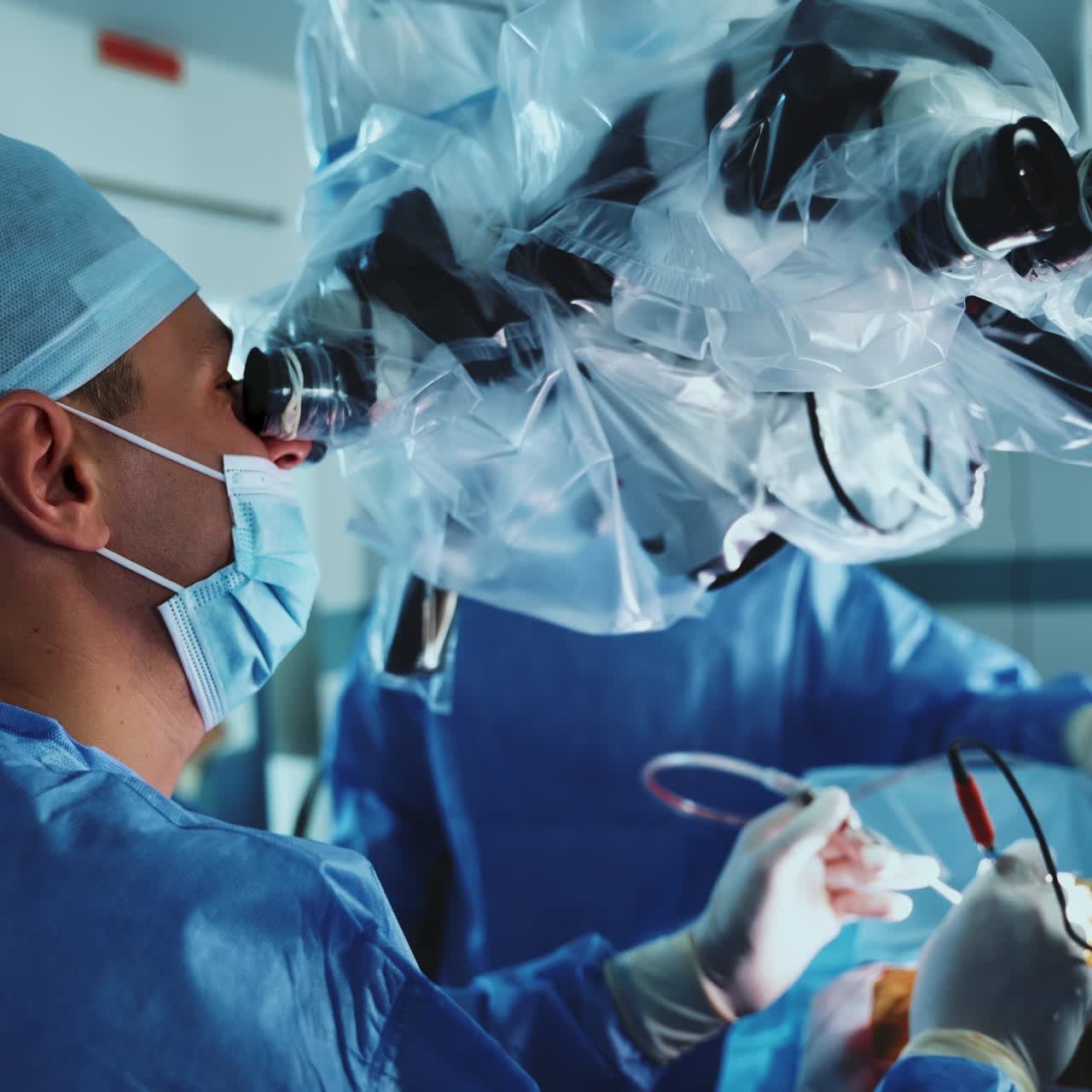 Professional neurosurgeons use electronic tools at operation and look into microscope. Focused doctors communicate during operation