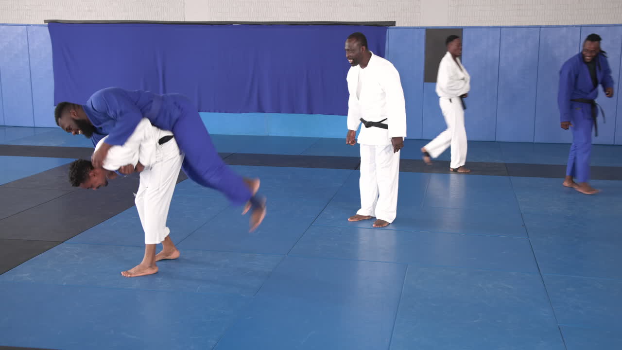 Practicing judo, athletes in white and blue uniforms training on mats