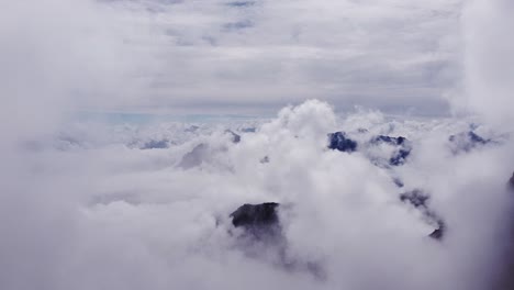 beautiful cinematic aerial flying through scenic white clouds in heavenly sky with mountain top peaks looking through cloudscape