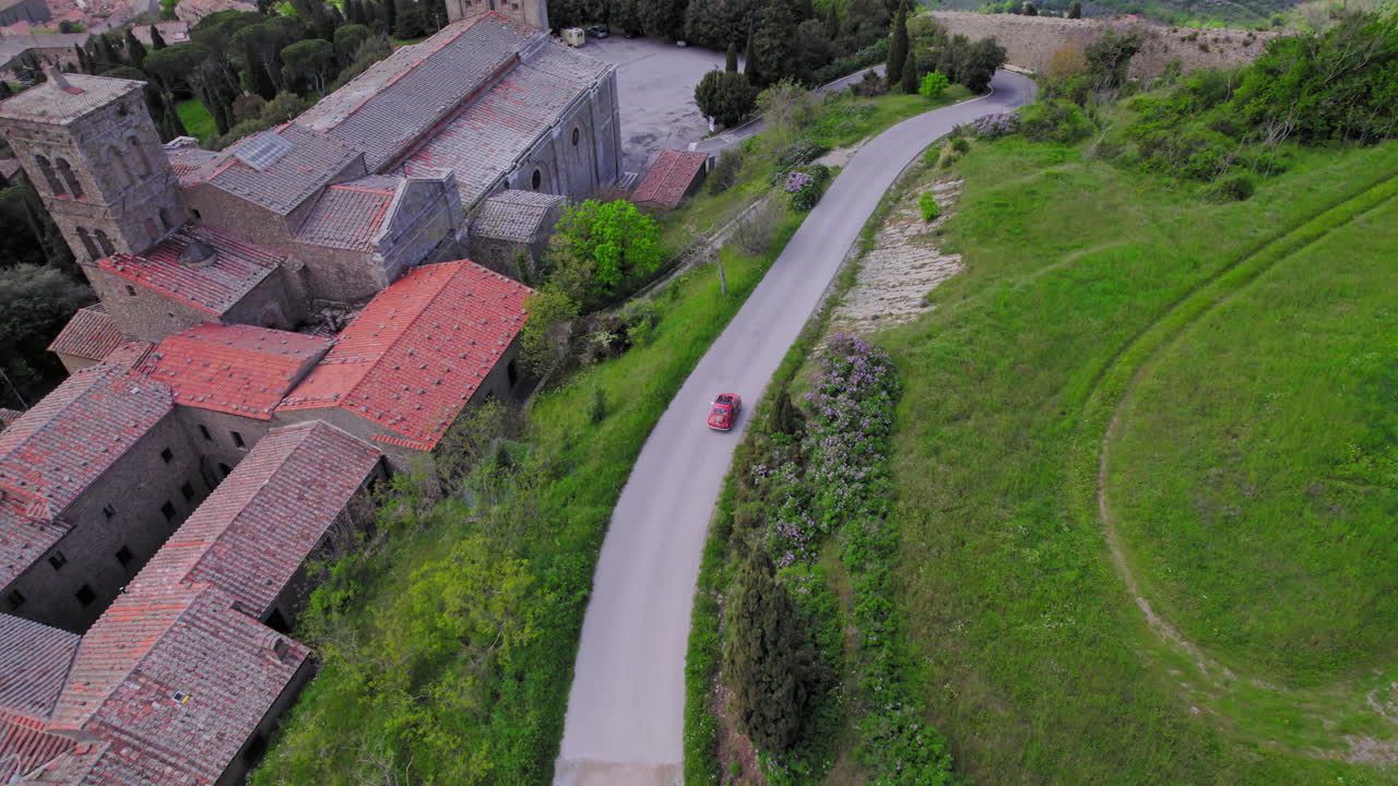 환상적인 파노라마와 함께 토스카니아 시골에서 운전하는 귀여운 작은 빨간 차의 공중 촬영