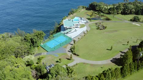 Top-view-aerial-shot-of-a-luxurious-private-resort-on-the-side-of-a-cliff-surrounded-by-lush-green-foliage