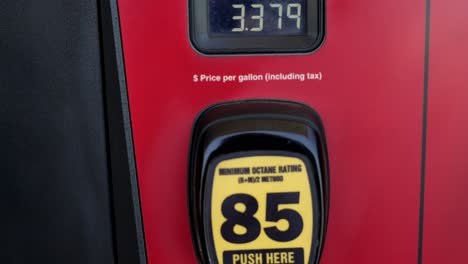 red and black gas pumps with prices super high over three dollars, panning top to bottom to show unleaded, regular grade fuel prices at 3