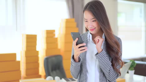 business smiling young asian woman with smartphone in hand exults