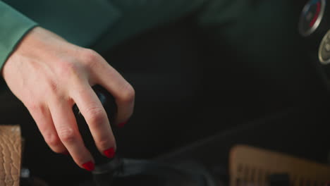 female driver hand shifts gear-lever of modern automobile