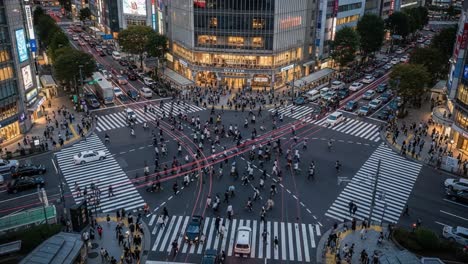 aerial view of a busy city intersection at dusk with light trails and blurred pedestrians