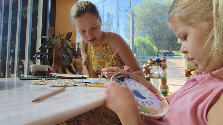 Madre e figlia che dipingono un piatto di ceramica insieme
