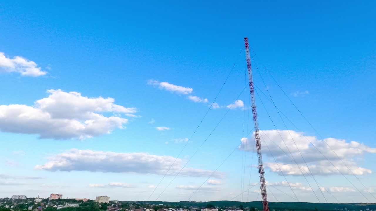 Little white clouds transforming in the clear blue sky. Amazing timelapse of the clouds over the city and television tower.