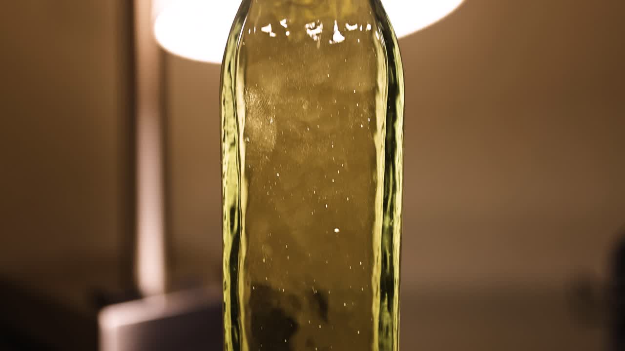 Close-up of olive-toned liquid in a glass bottle with reflections