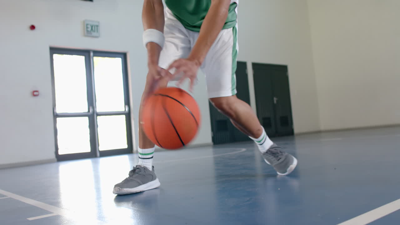 Young biracial man plays basketball indoors