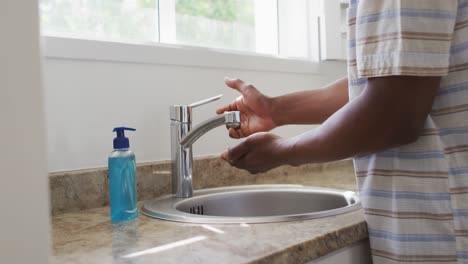 mid section of man washing his hands in the sink