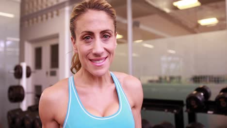 Mujer-Súper-En-Forma-Bebiendo-De-Una-Botella-De-Agua-Y-Sonriendo