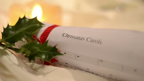 christmas carol music sheet with holly and candlelight