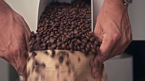 pouring roasted coffee beans into a paper bag