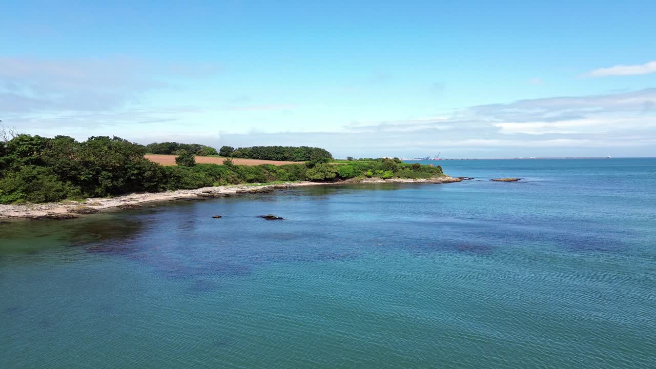 Welsh countryside farmland coast aerial view flying over clear turquoise blue sea in Holyhead