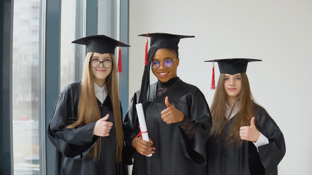tres estudiantes femeninas de diferentes razas con un diploma en la mano. graduados con túnicas negras y sombreros cuadrados miran a la cámara con una sonrisa. gran para la educación superior en europa y los estados unidos