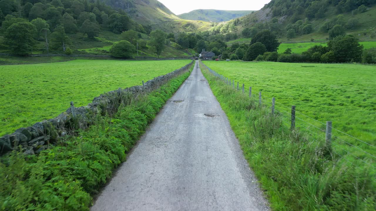 여름날 먼 농장과  ⁇ 빛이 비치는 산을 향해 그늘진 녹색 계곡의 시골 길을 천천히 내려가고 있습니다.