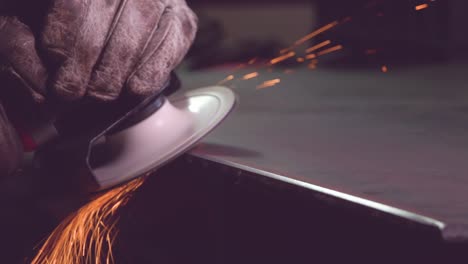 crop metal worker in gloves grinding edge of metal handiwork