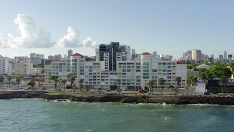 Car-traffic-on-road-along-Malecon-seafront-and-cityscape-in-background,-Santo-Domingo