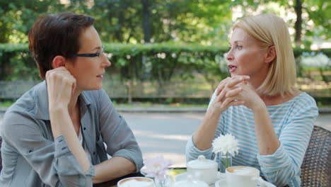 two women enjoying conversation in an outdoor cafe