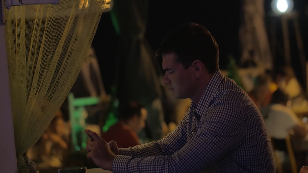 밤에는 야외 카페에서 셀을 가진 젊은 남자