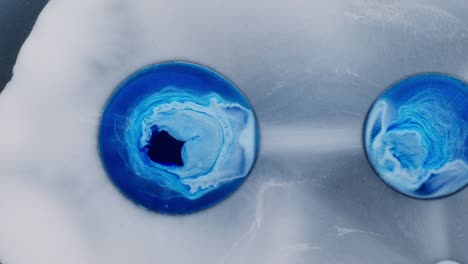 vibrant blue alcoholic ink forms abstract shapes in a white liquid surface macro