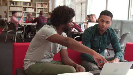 Männlicher-Universitätsstudent,-Der-Mit-Einem-Tutor-In-Der-Bibliothek-Arbeitet