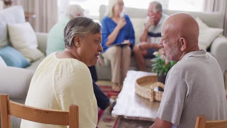 Senior-biracial-man-hugging-sad-diverse-senior-female-friend-at-support-group,-slow-motion