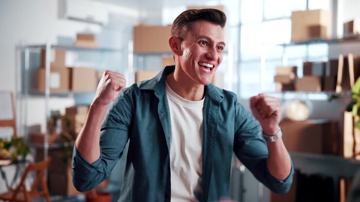 Giovane uomo entusiasta che festeggia il successo con un collega nell'ufficio di un magazzino