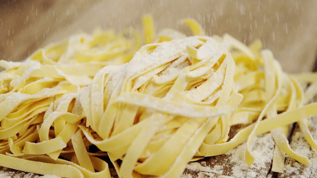 나무 바탕에 익히지 않은 tagliatelle 파스타에  ⁇ 어 나오는 밀가루의 클로즈업