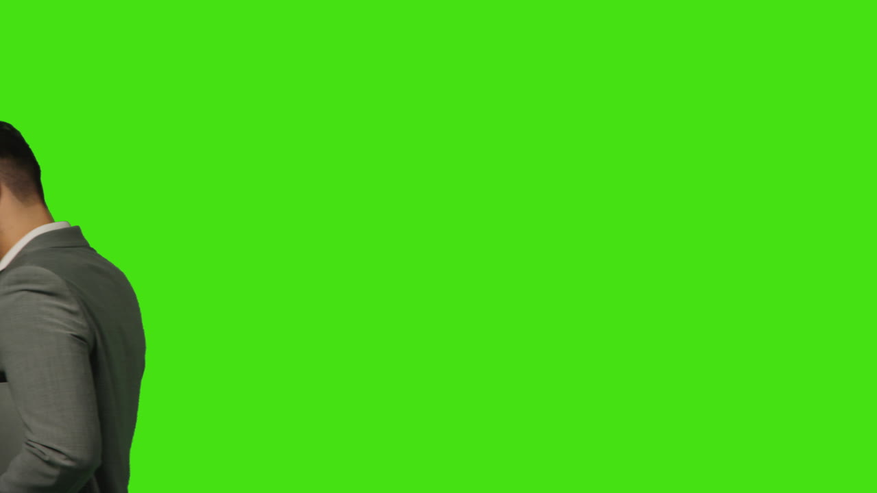 close-up di un uomo d'affari con un laptop che parla al cellulare che cammina attraverso la cornice contro lo sfondo dello schermo verde