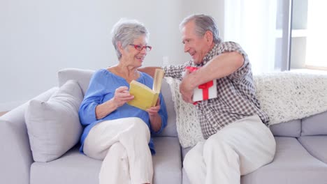 Cute-elderly-woman-receiving-present-from-husband