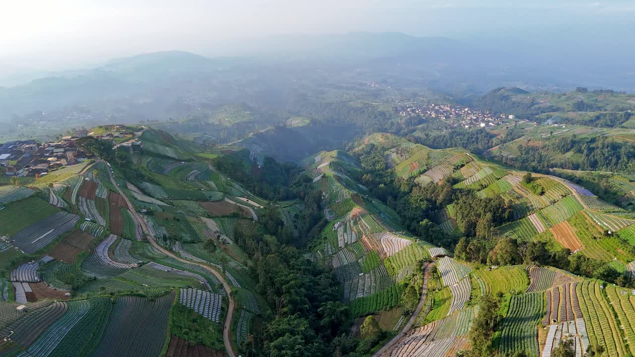 Majestic highland scenery with patterned farmlands wrapping around hills and valleys. Aerial view of Indonesia natural rural landscape