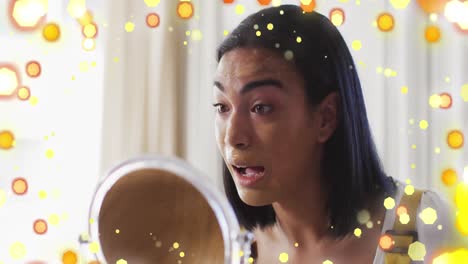 animation of light spots over biracial woman applying make-up