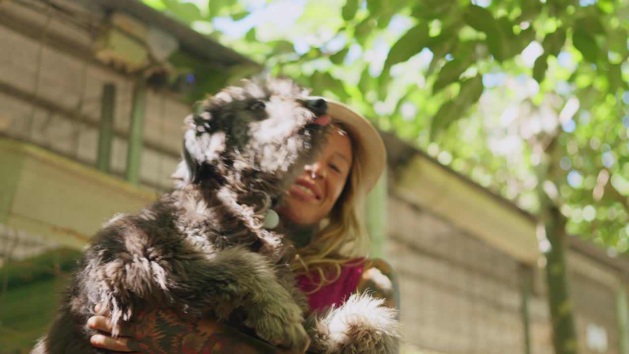 Donna che abbraccia e tiene in braccio il suo cane all'aperto in una giornata di sole
